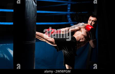 Kickboxer tritt in die Tasche. Training eines Profisportlers. Das Konzept von mma, Wrestling, muay thai. Gemischte Medien Stockfoto