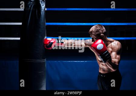 Kickboxer schlägt die Tasche. Training eines Profisportlers. Das Konzept von mma, Wrestling, muay thai. Gemischte Medien Stockfoto