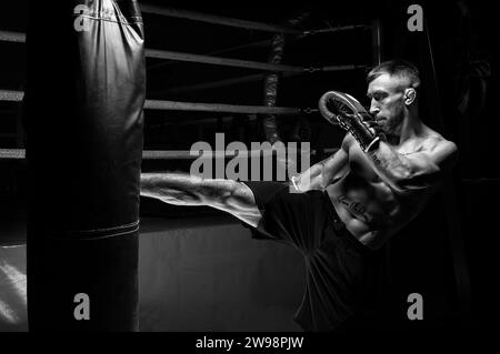 Kickboxer tritt in die Tasche. Training eines Profisportlers. Das Konzept von mma, Wrestling, muay thai. Gemischte Medien Stockfoto