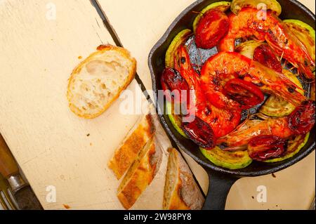 Gebratene Garnelen auf gusseiserner Pfanne mit Zucchini und Tomaten, Lebensmittelfotografie Stockfoto