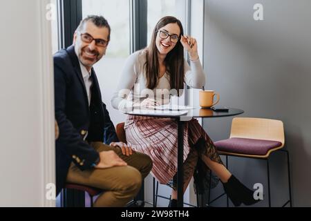 Geschäftspartner, die während der Arbeit Spaß mit ihren Mitarbeitern haben und lächeln. Positive Arbeitsatmosphäre. Stockfoto