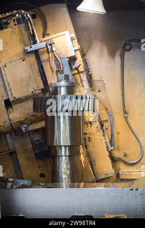 Die alte Maschine verarbeitet ein großes Metallteil. Schneiden und Kühlen des Produkts. Stockfoto