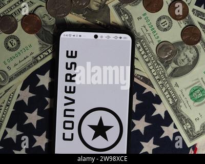 Deutschland. Dezember 2023. In dieser Fotoabbildung ist ein Converse Logo auf einem Smartphone mit US-Dollar-Banknoten und -Münzen im Hintergrund zu sehen. Quelle: SOPA Images Limited/Alamy Live News Stockfoto