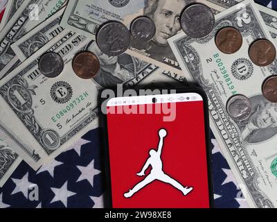 Deutschland. Dezember 2023. In dieser Fotoabbildung ist ein Air Jordan Logo auf einem Smartphone mit US-Dollar-Banknoten und -Münzen im Hintergrund zu sehen. (Foto von Igor Golovniov/SOPA Images/SIPA USA) *** ausschließlich für redaktionelle Nachrichten *** Credit: SIPA USA/Alamy Live News Stockfoto