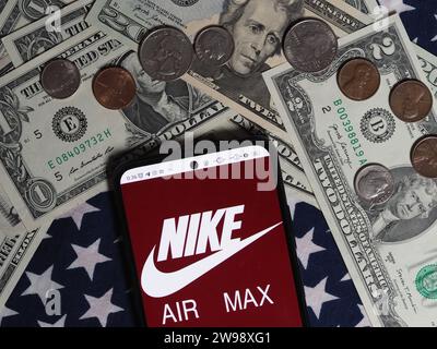 Deutschland. Dezember 2023. In dieser Fotoabbildung ist ein Nike Air Max Logo auf einem Smartphone mit US-Dollar-Banknoten und -Münzen im Hintergrund zu sehen. (Foto von Igor Golovniov/SOPA Images/SIPA USA) *** ausschließlich für redaktionelle Nachrichten *** Credit: SIPA USA/Alamy Live News Stockfoto