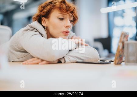 Die junge rothaarige Geschäftsfrau macht eine Pause, indem sie an ihrem Schreibtisch ein Nickerchen macht Stockfoto