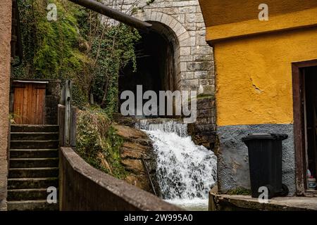 Ein malerischer Blick auf einen Wasserfall, der die Felsen in einem alten Dorf herunterstürzt Stockfoto