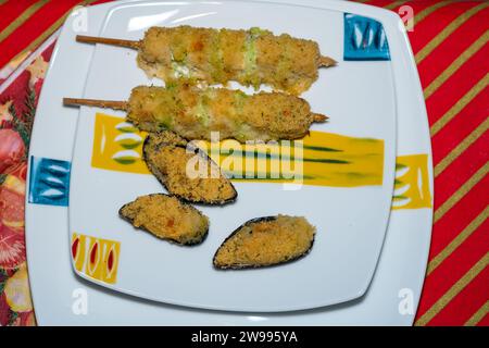 Gericht von oben mit Spießen von Skorpionfischen und Zucchini und Jakobsmuscheln au Gratin. Gesundes Essen für ein Fischmenü. Stockfoto