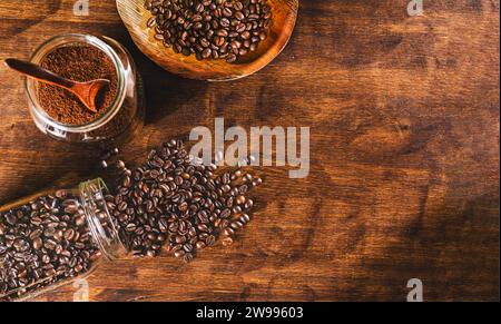Die Kaffeebohnen liegen auf einem Holztisch neben einem anderen Topf mit gemahlenem Kaffee und einer Schüssel mit mehr Bohnen. Stockfoto