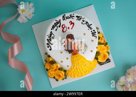Eine Nahaufnahme einer weißen Geburtstagskuche mit einem Mädchen drauf mit gelbem Kleid und Blumen Stockfoto