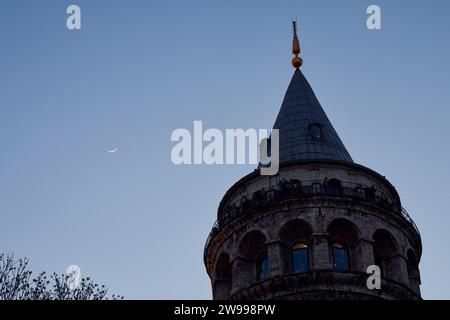 Ein beeindruckendes Niedrigwinkelfoto des berühmten Galatenturms in Istanbul, Türkei, beleuchtet am Abendhimmel Stockfoto