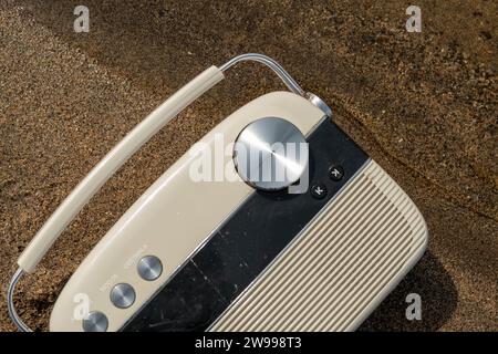 Ein weißes Radio im Vintage-Stil, das auf einem Holzboden sitzt und von einem schwarz-weiß karierten Muster umgeben ist Stockfoto