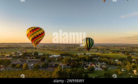 Bei Sonnenaufgang an einem sonnigen Sommermorgen können Sie mehrere Heißluftballons aus der Luft sehen, die im ländlichen Pennsylvania von Farmland abfliegen Stockfoto