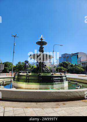 Eine ruhige Parkszene mit einem dekorativen Brunnen, beleuchtet von Straßenlaternen und umgeben von einem Gebäude Stockfoto