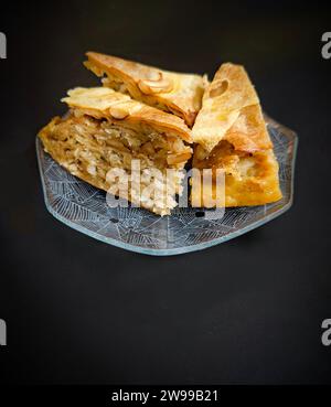 Dieses köstliche Bild zeigt einen weißen Teller, gefüllt mit einer Vielzahl von Blätterteig und frischem, farbenfrohen Obst auf einem Holztisch Stockfoto