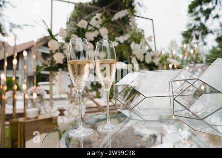 Drei elegante Gläser Rotwein auf einem weiß gekleideten Tisch im Garten, perfekt für eine Hochzeitsfeier Stockfoto