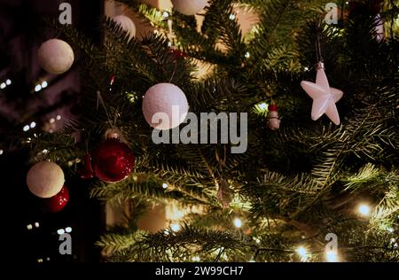 Die Weihnachtskiefer mit weißen dekorativen Kugeln, Sternen und Lichtern im Hintergrund Stockfoto