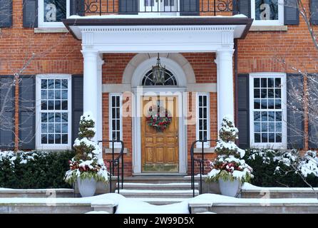 Haus im Winter mit eleganter Holzmaserung Eingangstür mit Weihnachtskranz Stockfoto