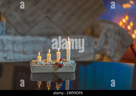 Blick auf vier brennende Kerzen in einem traditionellen Adventskerzenhalter als Teil der Weihnachtsfeier vor einem verschwommenen Hintergrund. Stockfoto