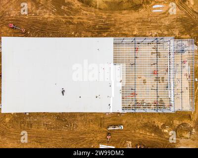 Ein Blick aus der Vogelperspektive auf das Grundgerüst einer riesigen Industrieanlage mit Materialien und Erdbewegern, die den frühen Bau prägten Stockfoto