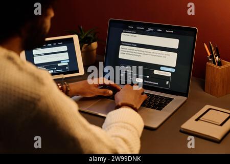 Junger männlicher KI-Designer, der an einem neuen Projekt arbeitet, während ich vor dem Laptop sitze, mit Daten auf dem Bildschirm und diese Informationen nutze Stockfoto