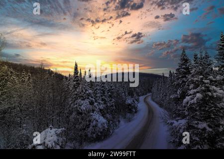 Eine malerische Winterlandschaft mit einer schneebedeckten Straße durch den Wald. Laurentides, Quebec Stockfoto