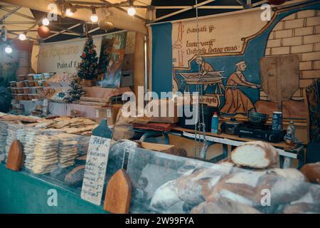 Dieses Bild zeigt einen belebten Marktbereich mit einer Fülle von frisch gebackenem Brot auf Holztafeln Stockfoto