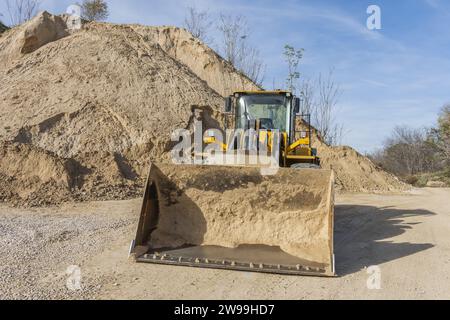 Ein Bagger stoppte in einem Arbeitsbereich mit einem Berg aus Sand und Kies auf dem Boden Stockfoto