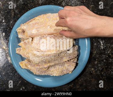 Kochen Sie das Fischfilet zum Braten in der Pfanne, indem Sie es in eine Mischung aus weißem Mehl und Maismehl tauchen. Hausmannskonzept. Stockfoto