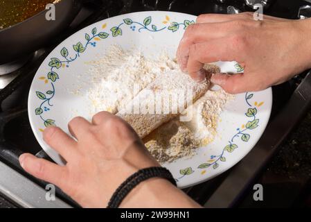 Kochen Sie das Fischfilet zum Braten in der Pfanne, indem Sie es in eine Mischung aus weißem Mehl und Maismehl tauchen. Hausmannskonzept. Stockfoto