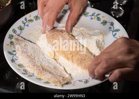 Kochen Sie das Fischfilet zum Braten in der Pfanne, indem Sie es in eine Mischung aus weißem Mehl und Maismehl tauchen. Hausmannskonzept. Stockfoto