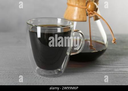 Glas- und chemex-Kaffeemaschine mit leckerem Tropfkaffee auf grauem Holztisch, Nahaufnahme Stockfoto