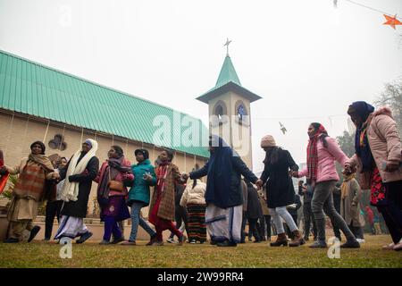 Srinagar, Indien. Dezember 2023. Christliche Gläubige tanzen vor der katholischen Kirche der Heiligen Familie an einem Weihnachtstag in Srinagar. Die umstrittene Himalaya-Region Kaschmirs hat eine winzige Bevölkerung von Christen, von denen Hunderte an Weihnachten an der Messe in der katholischen Kirche der Heiligen Familie teilnehmen und für Frieden in Kaschmir und Palästina beten. Viele kommen in Weihnachtskostümen, um Weihnachten zu feiern. Quelle: SOPA Images Limited/Alamy Live News Stockfoto