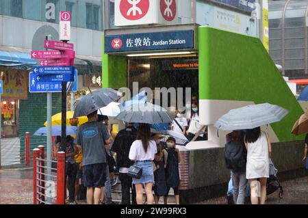 Fußgänger mit Regenschirmen am Ausgang C2 der Jordan Station, einer MTR-Station in der Gegend von Kwun Chung in Kowloon, Hongkong, bei starkem Regen (2021) Stockfoto
