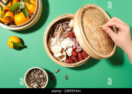 Bambus-Dampfkörbe bieten Platz für Mandarinen, Marmeladen, Jujubes und gesalzenes getrocknetes Obst auf einem Teetisch im Tet-Stil. Eine perfekte flache Lageneinstellung mit reichlich Kopier-Sp Stockfoto