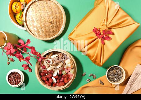 Der Bambusdampfer bietet Platz für Mandarinen, Marmelade, Jujubes und Gummibonbons. Melonenkerne und Sonnenblumenkerne werden in kleinen Schüsseln, einer Geschenkbox und einer Vase flo gelagert Stockfoto