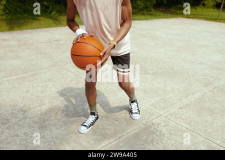 Zugeschnittenes Bild eines schwitzenden Sportlers, der auf dem Platz Streetball spielt Stockfoto