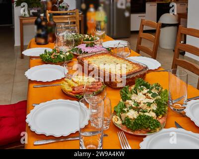 Ein wunderschön gedeckter Tisch für eine Silvesterfeier, mit eleganten Gläsern, Tellern und einer köstlichen Auswahl an Gourmet-Köstlichkeiten Stockfoto