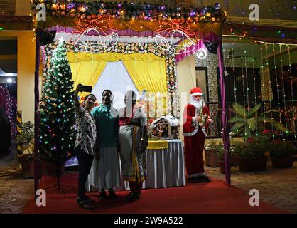 Mumbai, Indien. Dezember 2023. Die Leute machen ein Selfie in der Nähe einer Dekoration mit einem Weihnachtsmann, der vor einem Bungalow gehalten wird, um das Weihnachtsfest in Mumbai zu feiern. Weihnachten wird in aller Welt gefeiert, um an die Geburt Jesu Christi zu erinnern. Menschen aus der christlichen Gemeinde schmücken ihr Haus mit Weihnachtsbaum und Lichtern, tauschen Geschenke aus und Familienmitglieder versammeln sich zu einem fest, um den Anlass zusammen mit ihren nahen und lieben Menschen zu feiern. Quelle: SOPA Images Limited/Alamy Live News Stockfoto