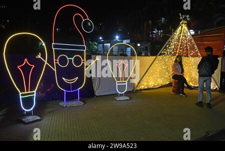 Mumbai, Indien. Dezember 2023. Eine Frau macht ein Foto in der Nähe einer Lichtinstallation auf einer Straße, um das Weihnachtsfest in Mumbai zu feiern. Weihnachten wird in aller Welt gefeiert, um an die Geburt Jesu Christi zu erinnern. Menschen aus der christlichen Gemeinde schmücken ihr Haus mit Weihnachtsbaum und Lichtern, tauschen Geschenke aus und Familienmitglieder versammeln sich zu einem fest, um den Anlass zusammen mit ihren nahen und lieben Menschen zu feiern. Quelle: SOPA Images Limited/Alamy Live News Stockfoto