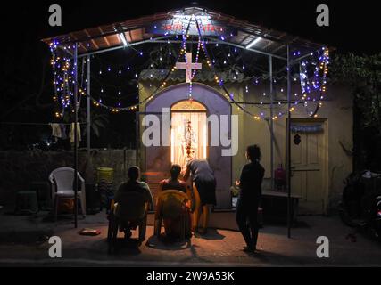 Mumbai, Indien. Dezember 2023. Die Menschen beten in der Nähe einer mit Lichtern geschmückten Grotte der Mutter Maria, um das Weihnachtsfest in Mumbai zu feiern. Weihnachten wird in aller Welt gefeiert, um an die Geburt Jesu Christi zu erinnern. Menschen aus der christlichen Gemeinde schmücken ihr Haus mit Weihnachtsbaum und Lichtern, tauschen Geschenke aus und Familienmitglieder versammeln sich zu einem fest, um den Anlass zusammen mit ihren nahen und lieben Menschen zu feiern. Quelle: SOPA Images Limited/Alamy Live News Stockfoto