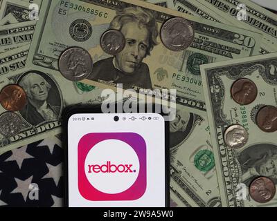 Deutschland. Dezember 2023. In dieser Fotoabbildung ist ein Redbox-Logo auf einem Smartphone mit US-Dollar-Banknoten und -Münzen im Hintergrund zu sehen. Quelle: SOPA Images Limited/Alamy Live News Stockfoto