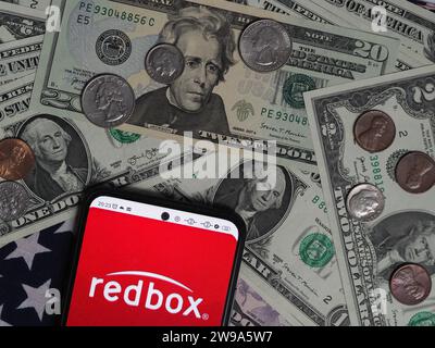 Deutschland. Dezember 2023. In dieser Fotoabbildung ist ein Redbox-Logo auf einem Smartphone mit US-Dollar-Banknoten und -Münzen im Hintergrund zu sehen. (Foto von Igor Golovniov/SOPA Images/SIPA USA) *** ausschließlich für redaktionelle Nachrichten *** Credit: SIPA USA/Alamy Live News Stockfoto