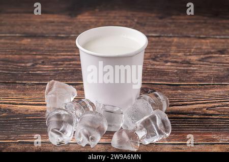 Kalte Milch in Pappglas zum Mitnehmen auf Holztisch Stockfoto