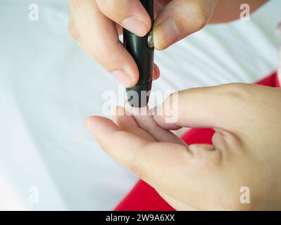 Frau mit lanzettfischchens am Finger, Diabetes Test überprüfung der Blutzuckerspiegel Stockfoto