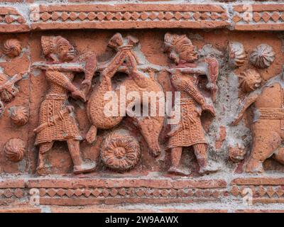 Nahaufnahme der geschnitzten Terrakotta-Jagdszene von Jägern, die Hirsche auf dem alten Govinda-Tempel im religiösen Komplex Puthia, Rajshahi, Bangladesch transportieren Stockfoto