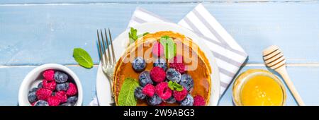 Teller mit leckeren traditionellen amerikanischen Pfannkuchen mit frischen Beeren und Sirup auf Küchentisch auf hellem Hintergrund Stockfoto