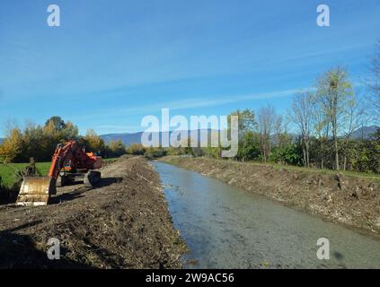 Großer Bagger am Flussufer bei Instandhaltungsarbeiten am Damm nach der Überschwemmung Stockfoto