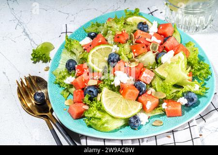 Sommer-Wassermelonensalat. Frischer roher grüner Salat mit Salat, Rucola, Wassermelonenscheiben, Heidelbeere, Feta-Käse und Honig Stockfoto
