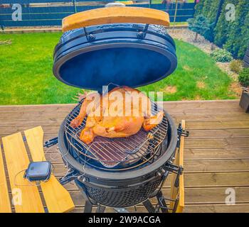 Die Türkei bereitet sich im Kamado-Grill über heißer Holzkohle auf der Gartenterrasse für die Barbecue-Party vor. Marinierter und ausgestopfter truthahn. Kochen im Freien. Schließen Stockfoto